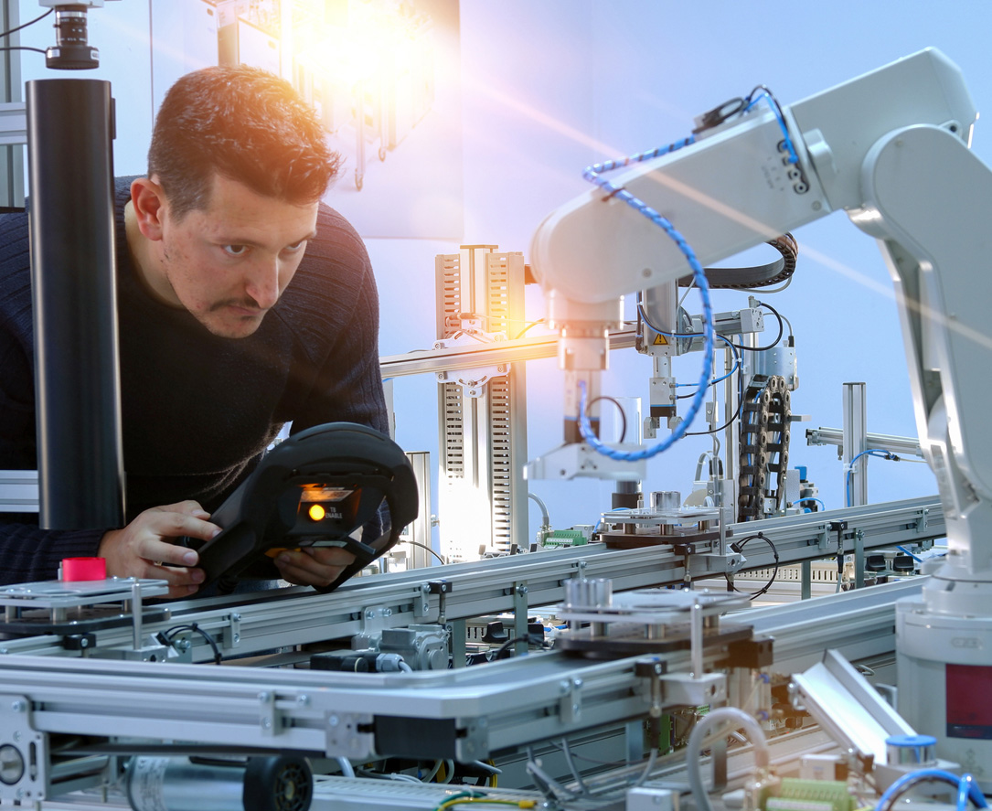 Man with moustache investigating advanced robotic automation system. Sharp light from background.